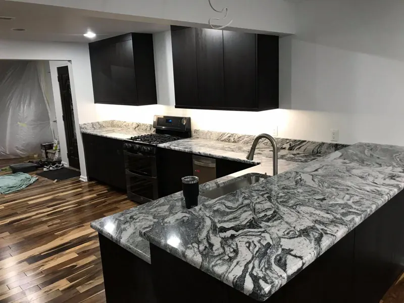 Swirled black and white granite island on black cabinets