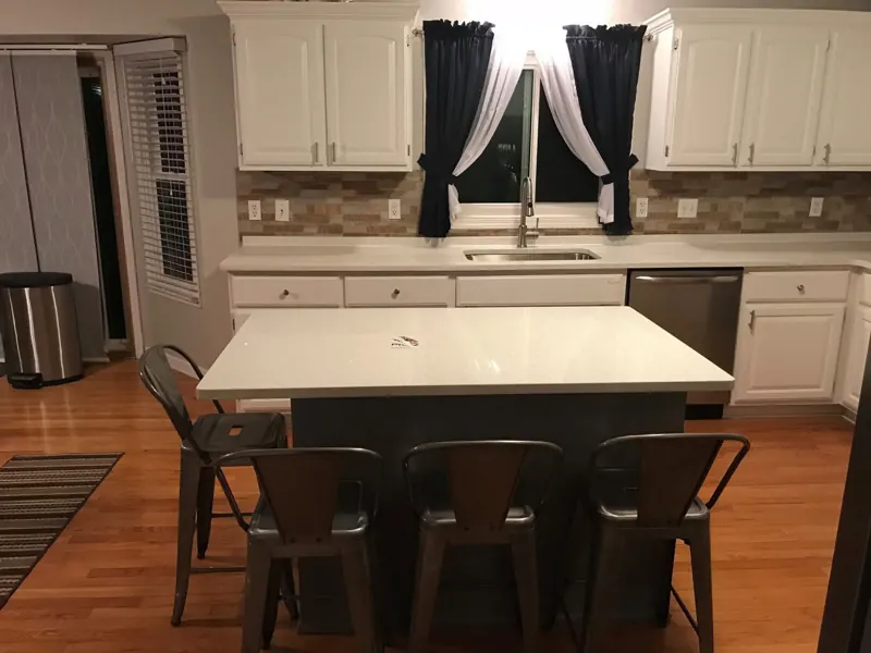 White kitchen island with a white top and dining stools